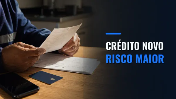 Trabalhador lê documentos financeiros ao lado de cartão bancário e celular, com a chamada Crédito novo, risco maior.
